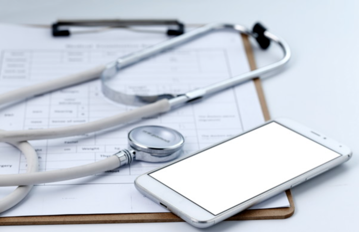 Stethoscope and mobile phone atop a clipboard